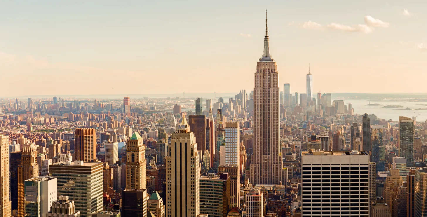 Aerial view of New York City skyline with the Empire State Building centered and other skyscrapers visible under a clear sky, highlighting the vibrant metropolis that is home to top professionals, including leading New York City tax whistleblower lawyers.