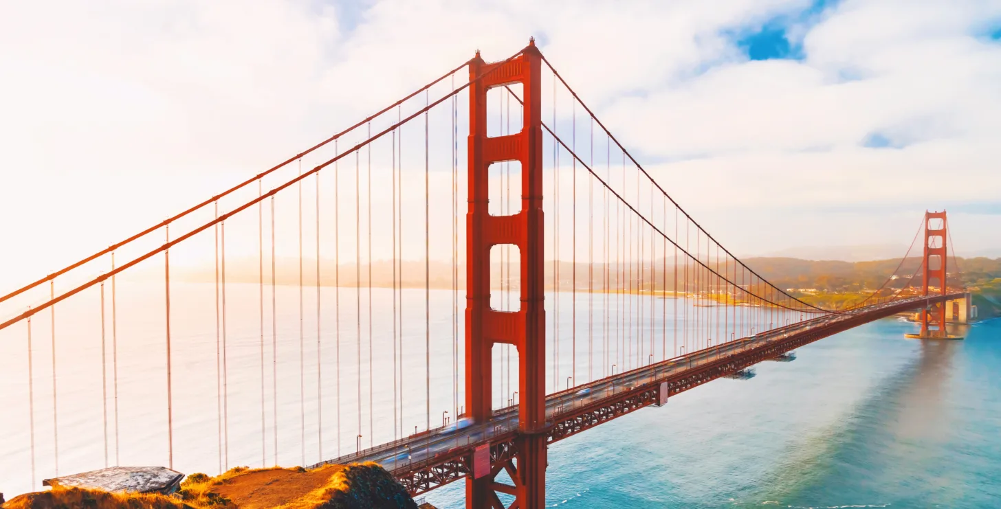 Golden Gate Bridge spans over water with blue sky and clouds in the background, photographed during daylight from a nearby elevated viewpoint—a classic scene often admired by visitors and even San Francisco healthcare fraud lawyers seeking a moment of respite from their busy caseloads.