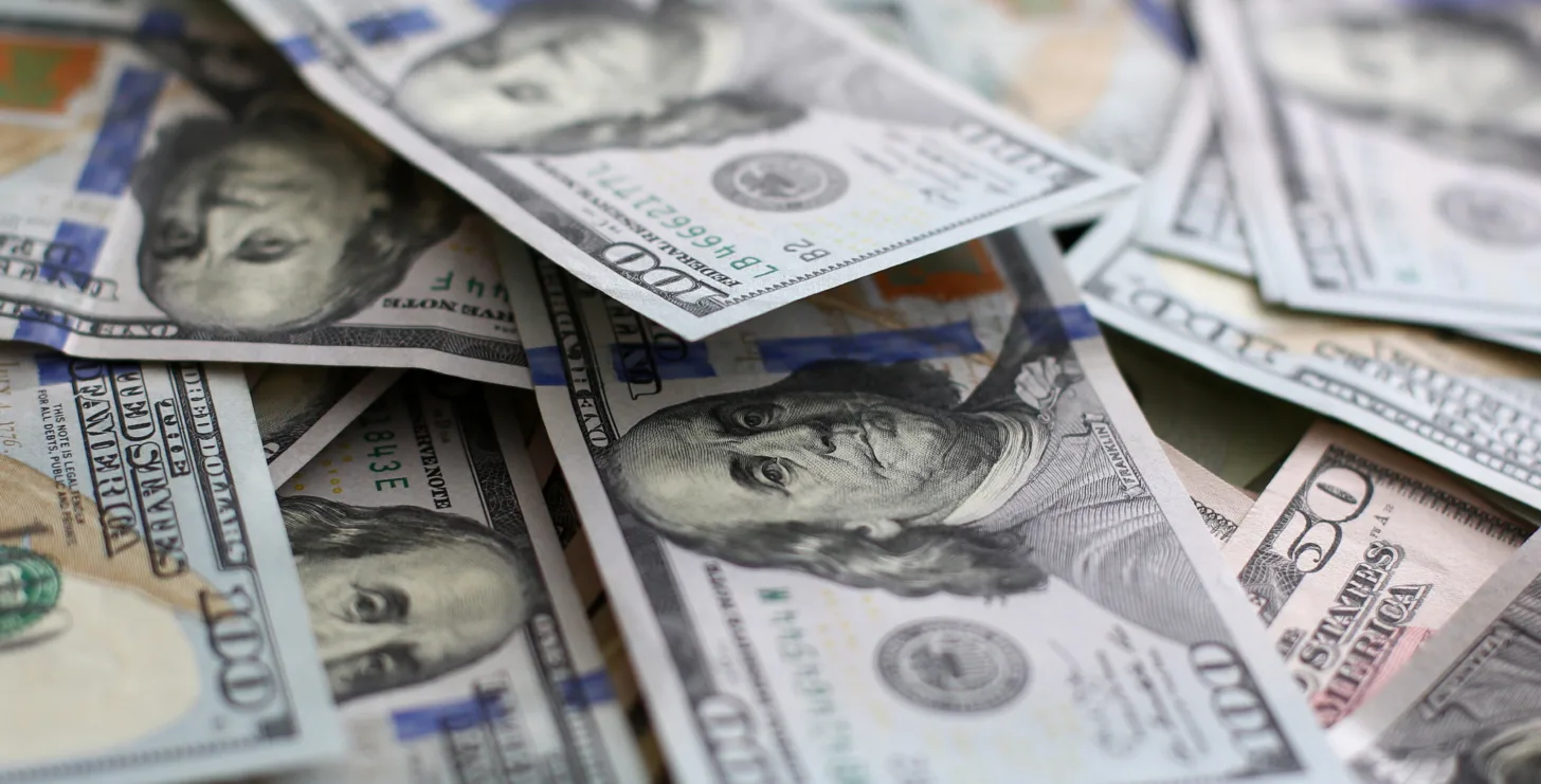 Scattered U.S. one hundred dollar bills featuring Benjamin Franklin’s portrait, displayed closely together—an image often associated with cases handled by a San Jose IRS whistleblower lawyer seeking justice in complex financial fraud investigations.