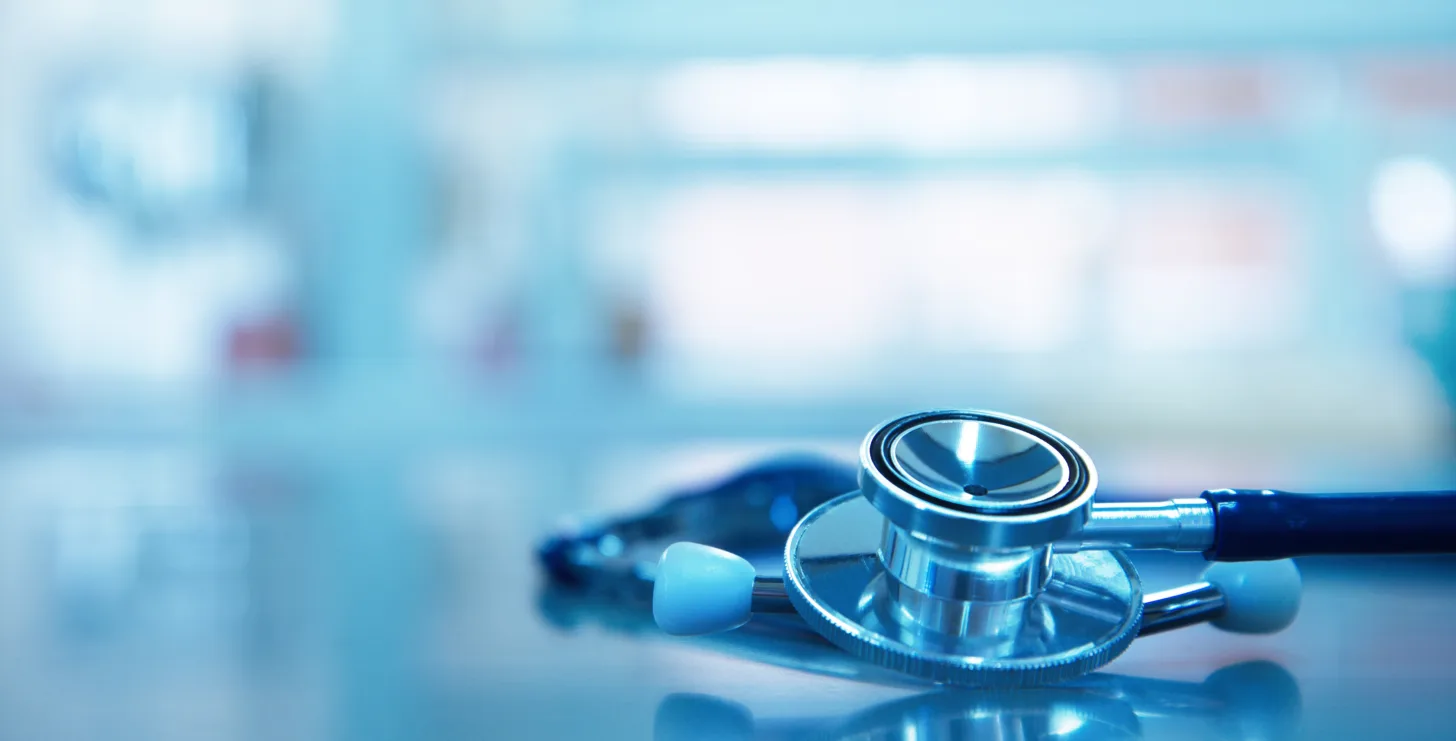 A stethoscope lies on a shiny surface in a medical setting, with a blurred background—an environment where New York Medicare whistleblower cases often begin to unfold.