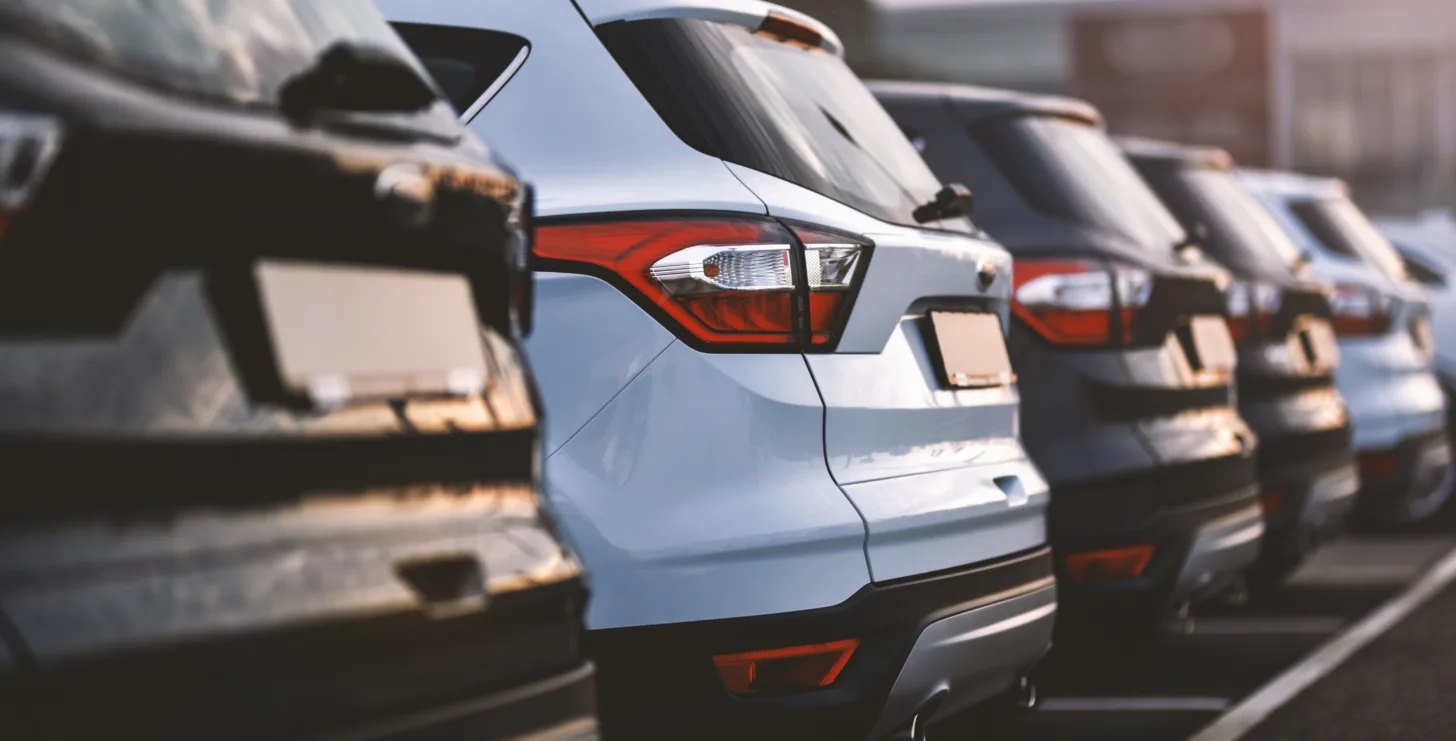 Row of parked SUVs in a parking lot, viewed from the rear at an angle, with sunlight reflecting off the vehicles—much like the fleet that might be found outside a busy law office specializing in high-stakes cases such as those handled by Silicon Valley CFTC whistleblower attorneys or a New York City tax whistleblower lawyer.