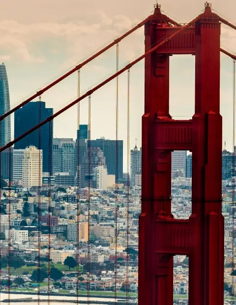 Golden Gate Bridge tower in the foreground with downtown San Francisco buildings and skyline visible in the background, a powerful reminder of the innovation that draws Silicon Valley CFTC whistleblower attorneys to the Bay Area.