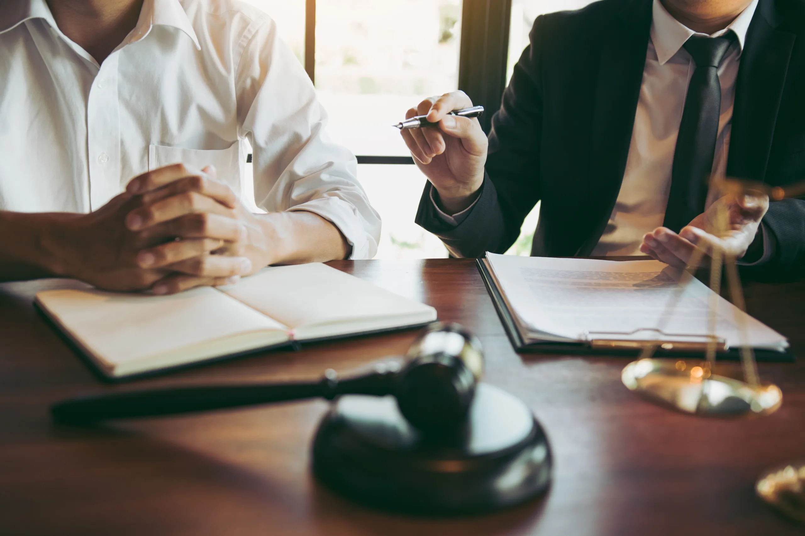 Home Two Boston SEC whistleblower attorneys in business attire sit at a desk with legal documents and a wooden gavel.